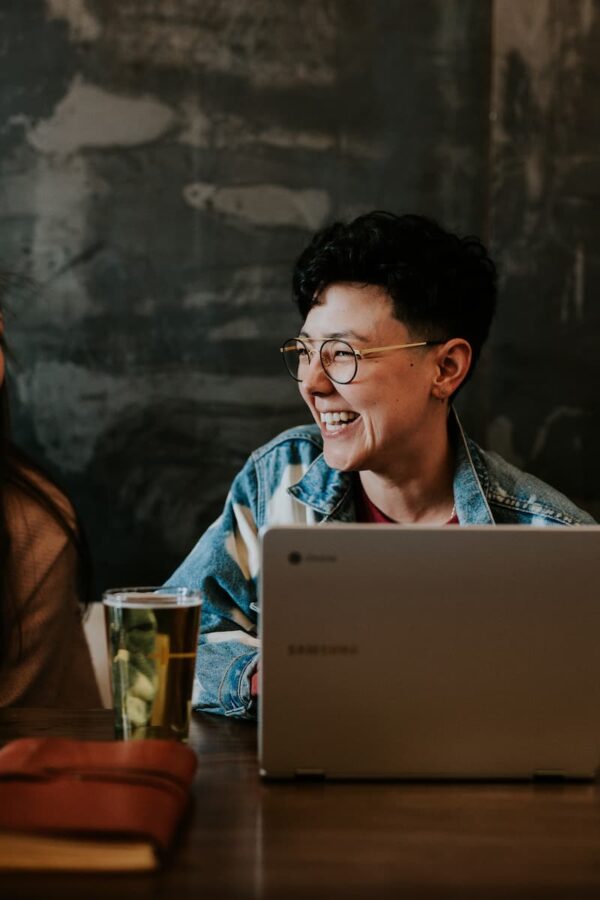 Smiling young woman with coffee and laptop by Brooke Cagle via Unsplash